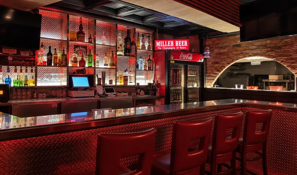 Fratelli’s full bar with red seating and illuminated bottle shelves